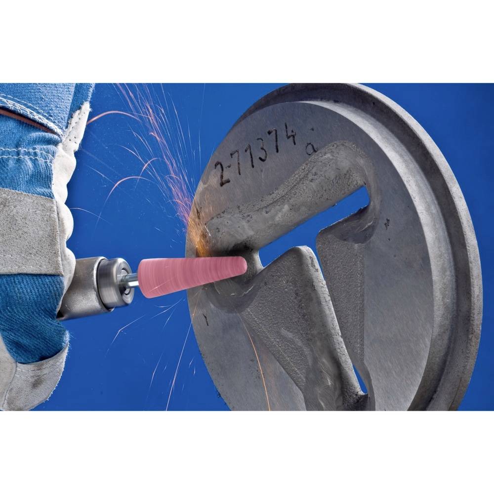 Ein Arbeiter in blauem Schutzanzug schleift mit einem rotierenden Werkzeug Metall. Funken fliegen vom Schleifpunkt weg.