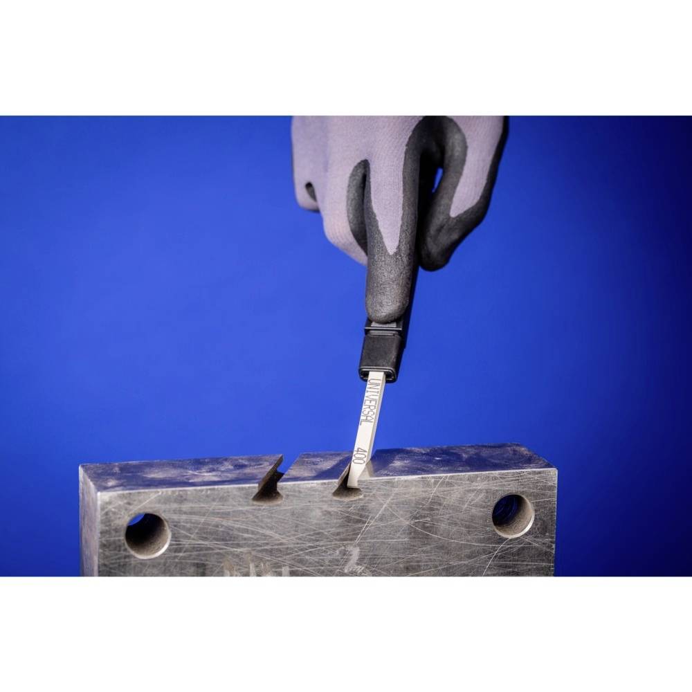 Eine Hand mit Handschuh hält ein Prüfgerät, das in eine Kerbe eines Metallblocks einführt. Hintergrund in Blau.