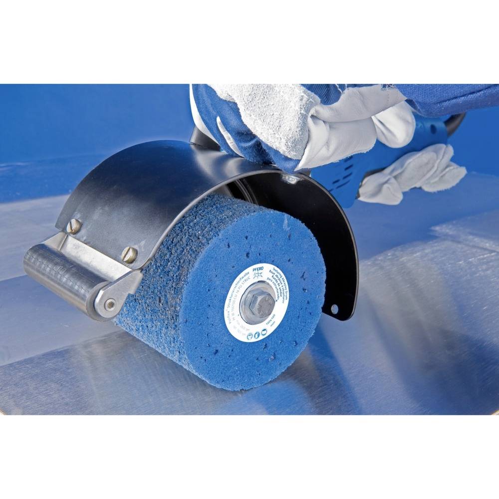 Gloved Hand hält eine blaue Schleifmaschine über eine Metalloberfläche, bereit zur Bearbeitung.