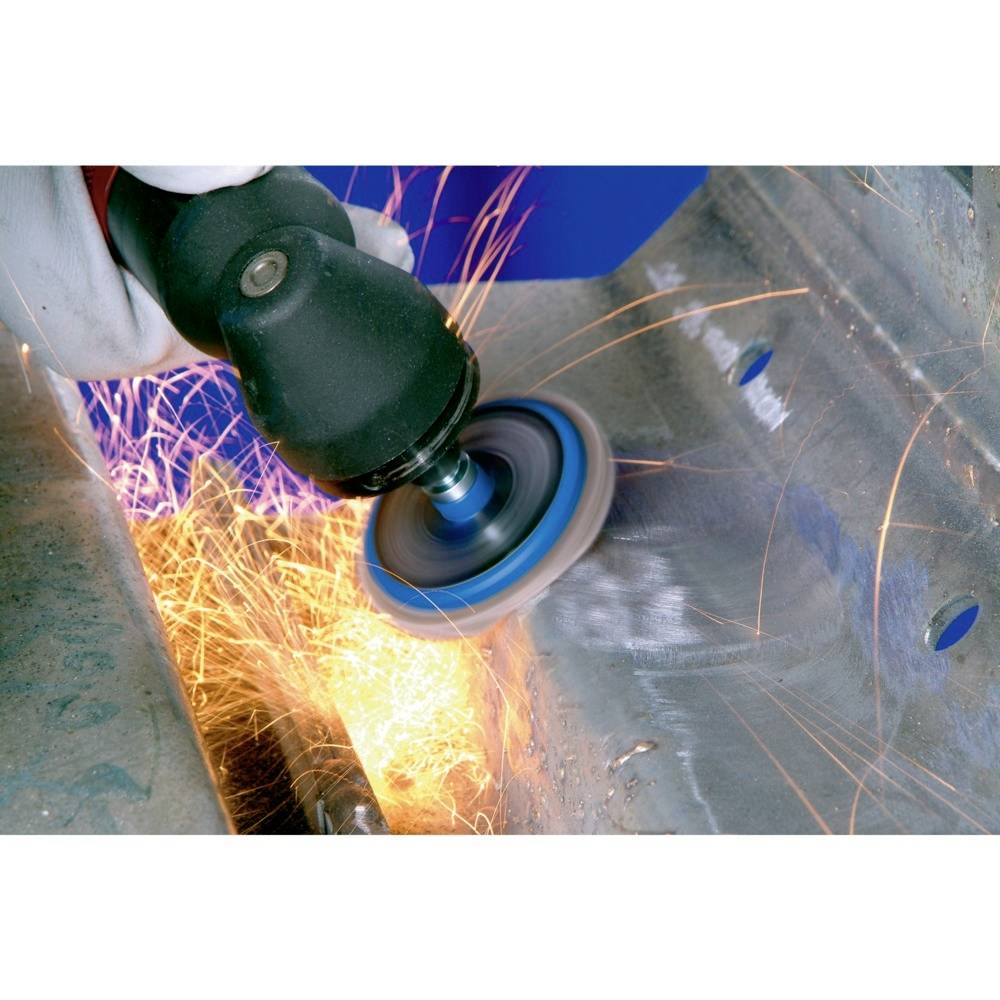 Eine Person schleift Metall mit einem Winkelschleifer, Funken fliegen. Nahaufnahme der Arbeitsfläche zeigt intensive Schleifarbeit.