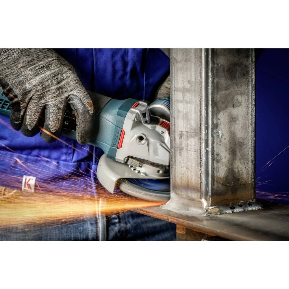 Eine Person schleift mit einem Winkelschleifer Metall, wobei Funken sprühen. Die Person trägt Handschuhe und eine blaue Arbeitssjacke.