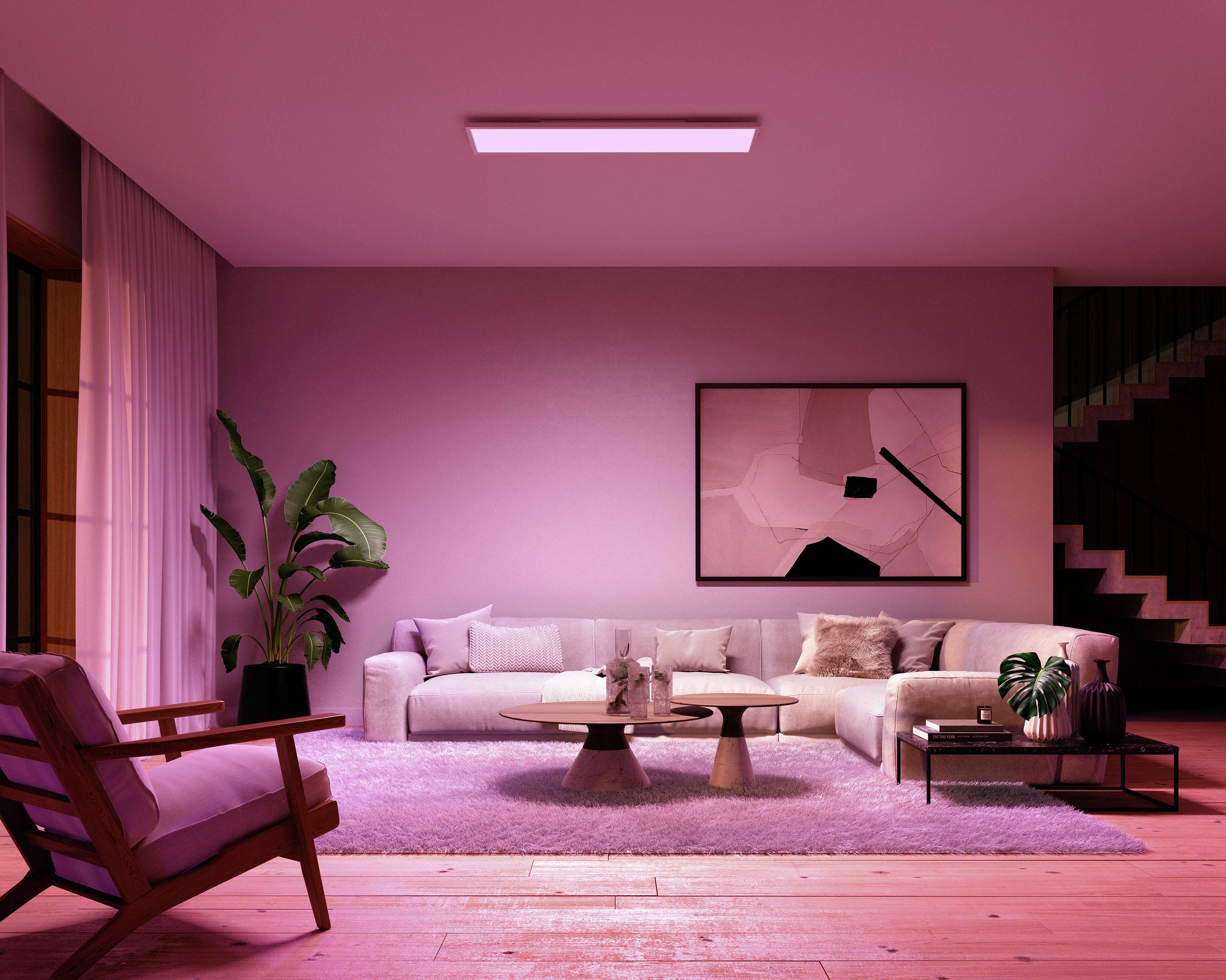 Ein modernes Wohnzimmer mit einem großen Sofa, umgeben von Pflanzen und Kunstwerken an der Wand. Die Beleuchtung schafft eine gemütliche Atmosphäre.