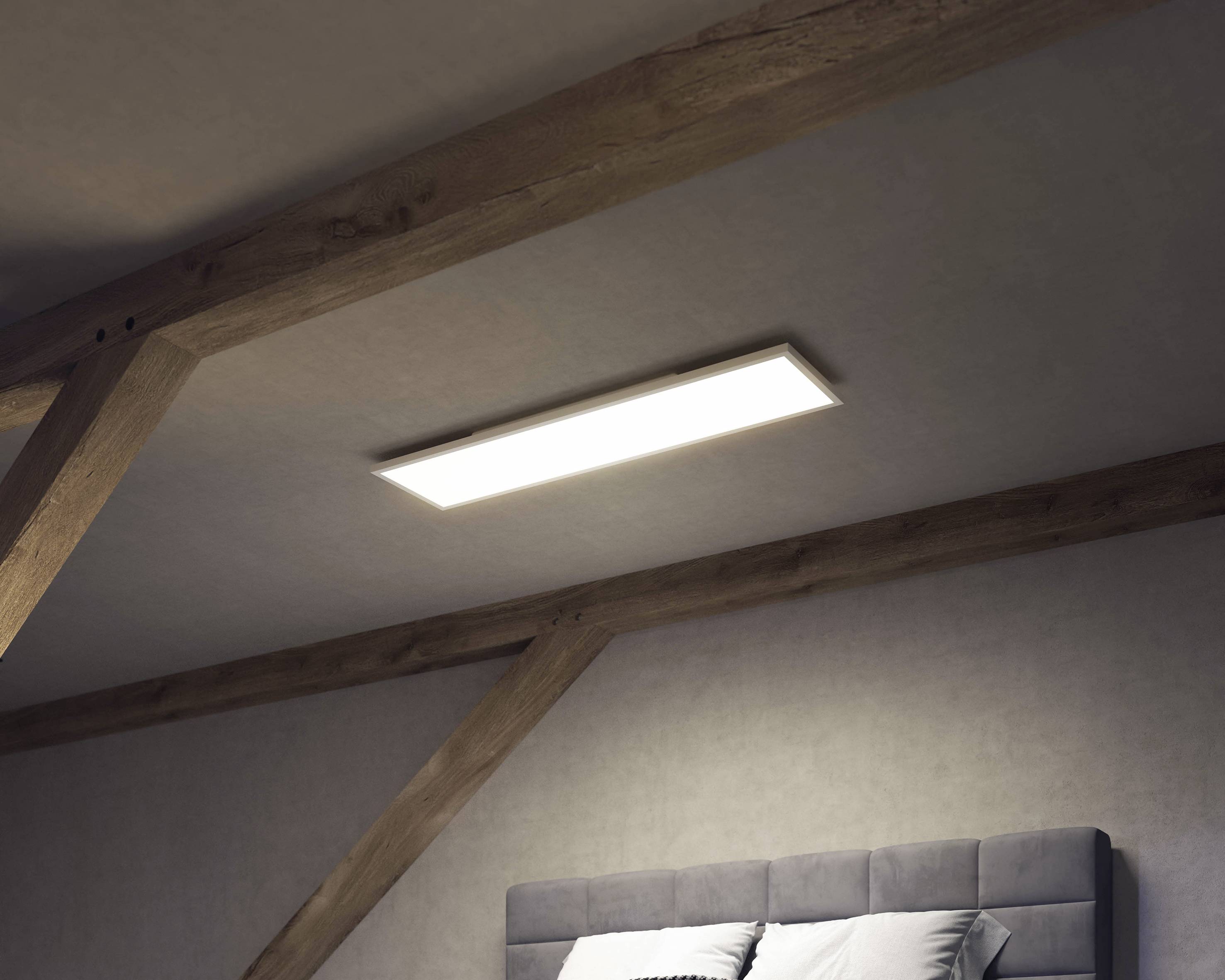 Eine rechteckige LED-Deckenleuchte in einem Raum mit Holzbalkenstruktur beleuchtet dezent die Szene über einem gepolsterten Bettkopfteil.