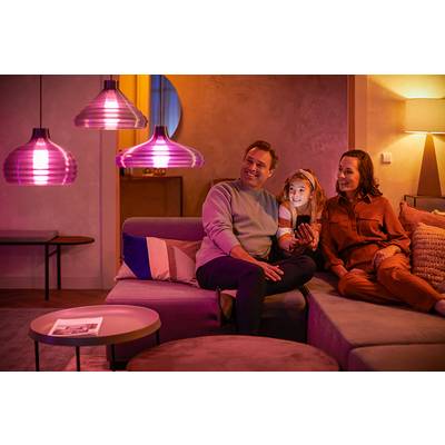 Eine Familie sitzt abends gemütlich auf dem Sofa in einem Wohnzimmer mit stimmungsvoller Beleuchtung.