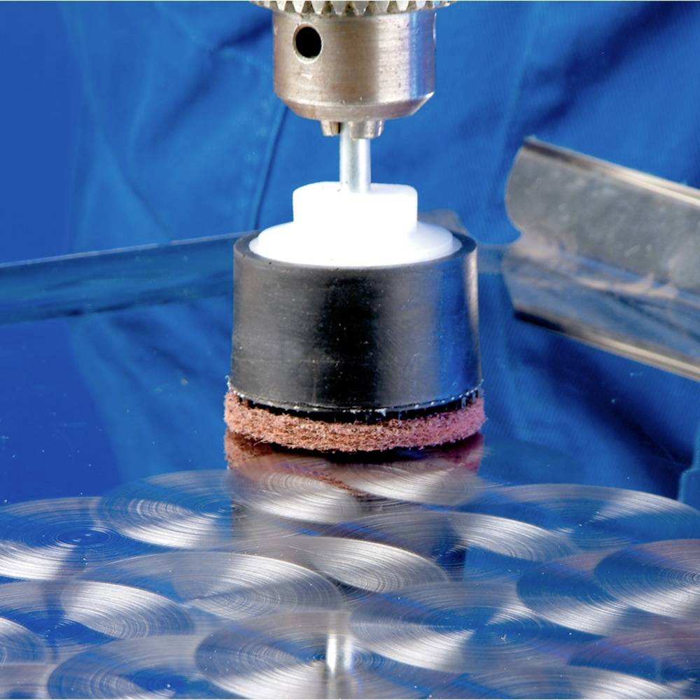 Eine Poliermaschine glättet eine Metalloberfläche. Der runde Polierkopf hinterlässt feine Schleifspuren, reflektiert im Licht.