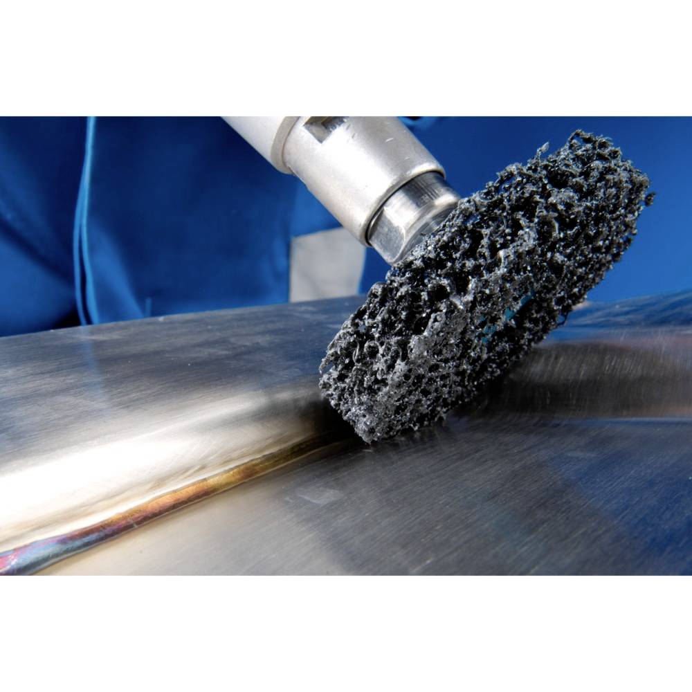 Eine Drahtbürste poliert eine Metalloberfläche. Sie entfernt Unregelmäßigkeiten und verleiht dem Metall ein glatteres Finish.