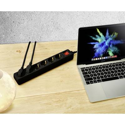 Laptop auf Holztisch neben einer Steckdosenleiste mit zwei eingesteckten Netzsteckern. Laptop zeigt bunte Bildschirmgrafik.