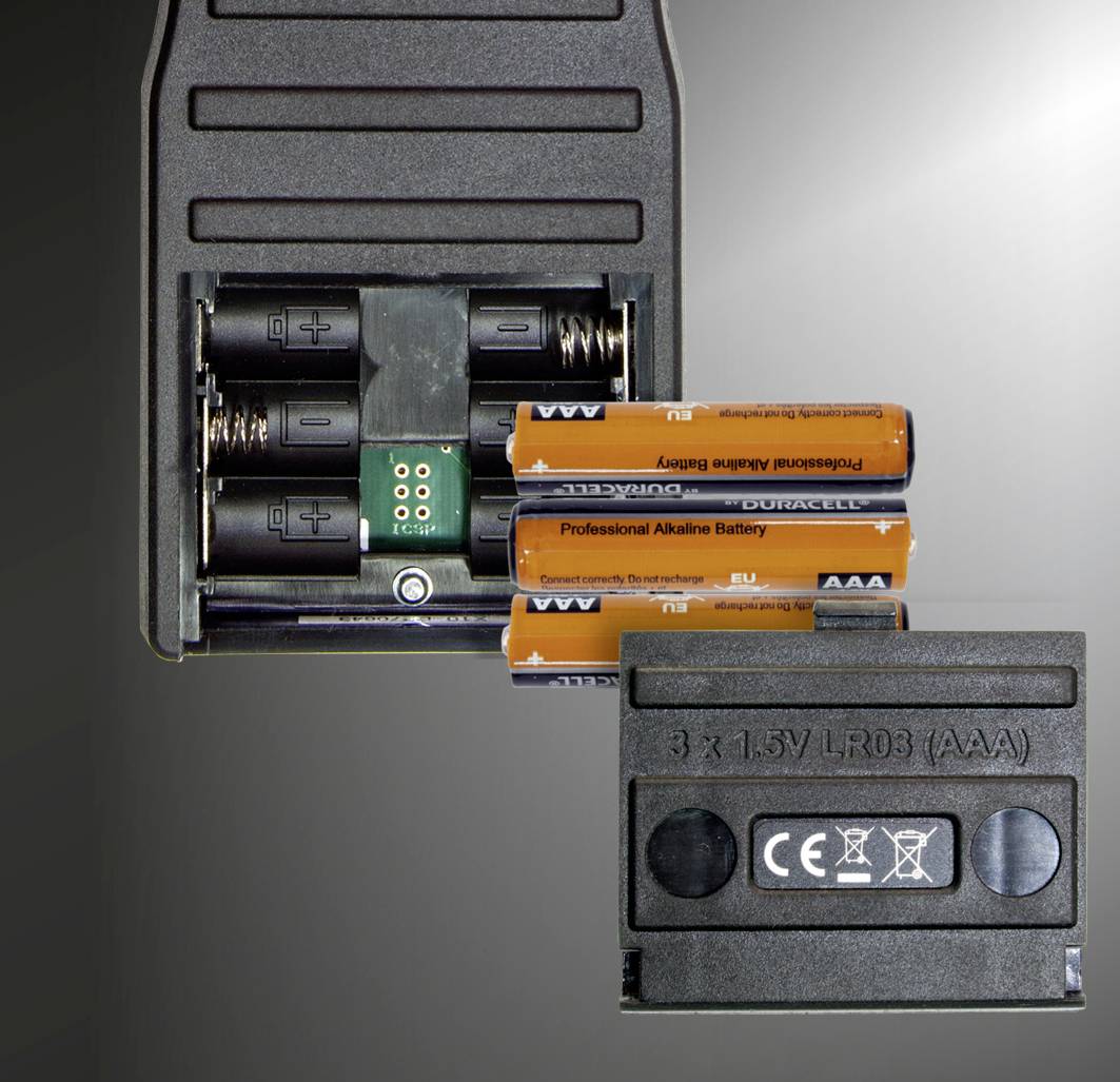Geöffnete Batteriefachabdeckung zeigt drei AAA-Batterien in einem Gerät. Text auf dem Deckel: '3 x 1.5V LR03 (AAA)' und Sicherheitssymbole.