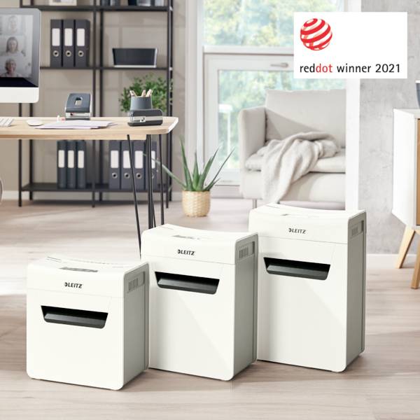 'Drei weiße Aktenvernichter von Leitz in einem modernen Büro mit Red Dot Award 2021 Logo im Hintergrund.'