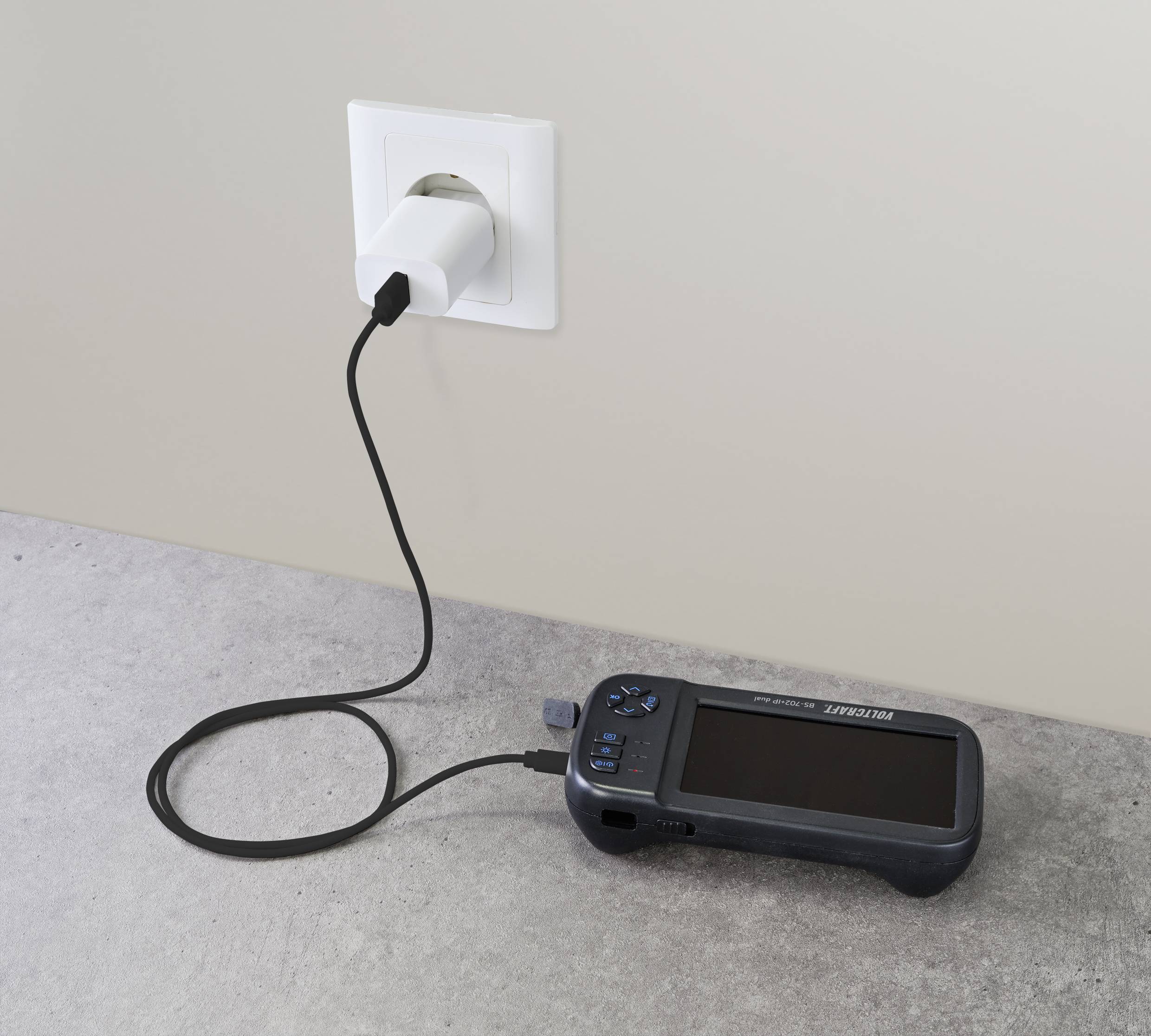 Ein tragbares elektronisches Gerät wird über ein USB-Kabel an einer Wandsteckdose aufgeladen.