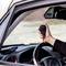 Person hält ein Funkgerät in der Hand eines Fahrerinnenautos. Im Hintergrund ist das Armaturenbrett mit Steuerelementen sichtbar.