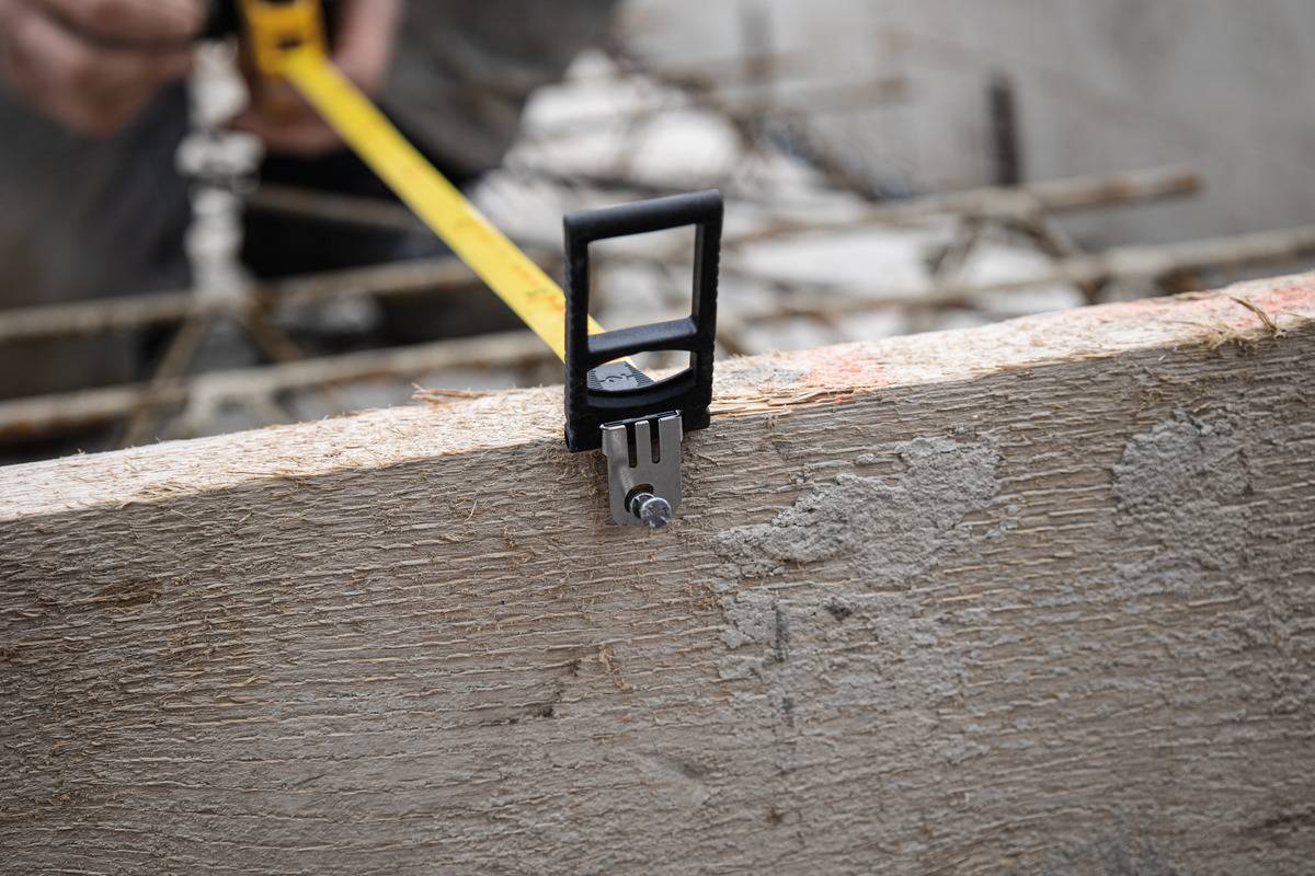 'Ein Mensch misst ein Holzbrett mit einem Maßband.'