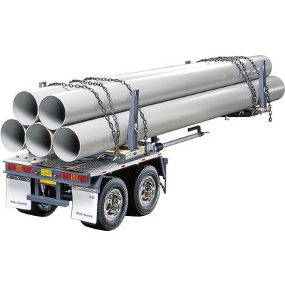 Ein LKW-Anhänger transportiert große, graue Rohre, die mit Ketten gesichert sind. Der Anhänger hat zwei Achsen und ist für Schwerlasten ausgelegt.