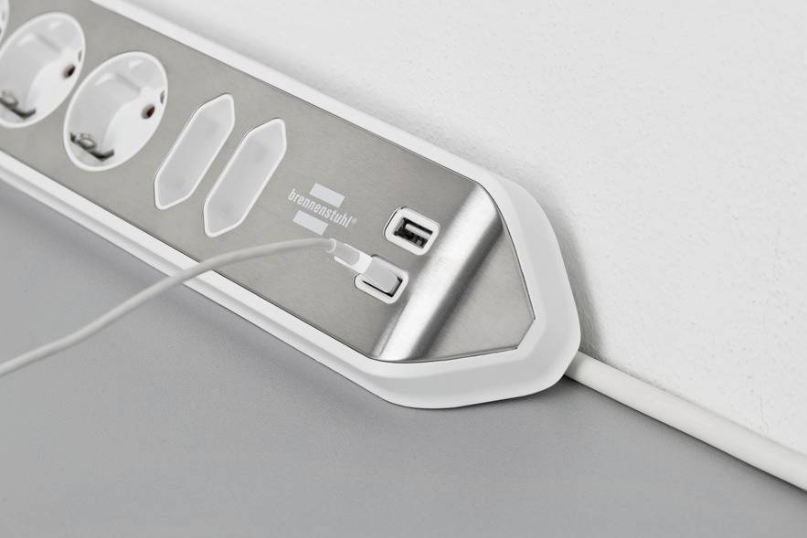 Mehrfachsteckdose mit drei Steckplätzen und zwei USB-Anschlüssen an der Wand. Ein USB-Kabel ist eingesteckt.