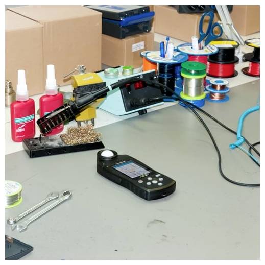 Elektronische Werkbank mit einem Lötkolben, Lothrollen, Werkzeugen und einem tragbaren Messgerät auf einem Tisch.