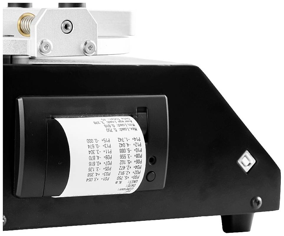 Ein Gerät druckt ein Papierstreifen mit Zahlen und Codes. Es wird möglicherweise für Messungen oder Berechnungen verwendet.