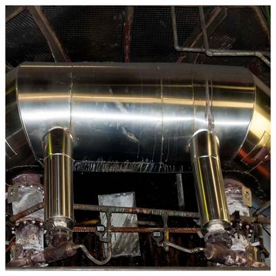 Glänzendes Metallleitungssystem und zwei vertikale Rohre, die mit rostigem Industriemaschinenbau in einem Maschinenraum oder Fabrikinneren verbunden sind.