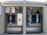 Ein offener Stromverteilerkasten mit mehreren farbigen Kabeln und Warnschildern; zeigt elektrische Installationen.