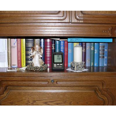 Ein Regal mit Büchern, darunter ein Standbild eines Engels, eine Kerze in einem Halter und ein Thermometer, das 38,1°C und 20,8% anzeigt.