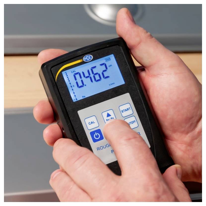 Hände halten ein tragbares Messgerät mit blauem Display, das '0,462' anzeigt, sowie Tasten für Kalibrierung, Start und Stopp.