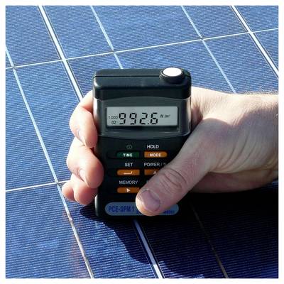 Hand hält ein Solarmessgerät über ein Photovoltaikpanel, zeigt eine Anzeige von 992,6 W/m².