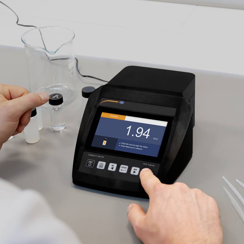 Ein Wissenschaftler kalibriert ein Trübungsmessgerät. Auf dem Display stehen '1.94 NTU', was den Trübungswert einer Flüssigkeit anzeigt.