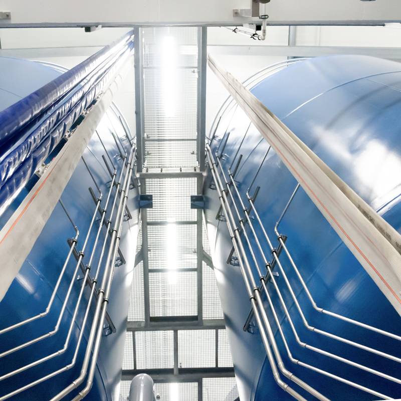 Blick zwischen zwei großen blauen zylindrischen Tanks mit Treppen in einem Industriegebäude. Symmetrische Anordnung der Elemente.