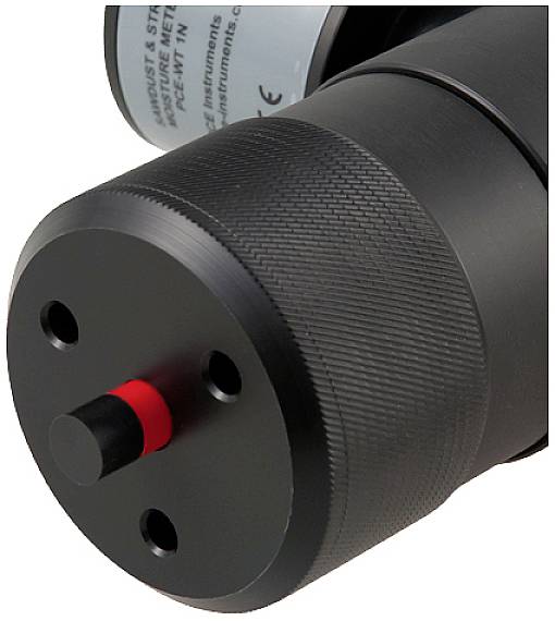 Ein schwarzes zylindrisches Gerät mit geriffelter Oberfläche und rotem Mittelknopf. Teil eines technischen Apparates.