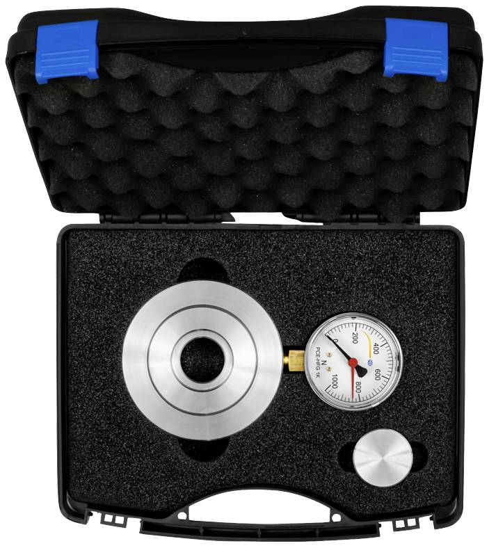 Ein offener schwarzer Koffer mit Schaumstoffeinlage zeigt einen runden Metallzylinder und ein Manometer.