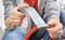 Eine Person wickelt silbernes Klebeband um einen roten Schlauch. Hände halten Band und Schlauch fest. Fokus liegt auf der Reparatur.