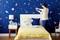 Eine Frau dekoriert eine Kinderzimmerwand mit Weltraummotiven. Das Bett ist mit einem gelben Musterüberwurf und Stern-Kissen geschmückt.