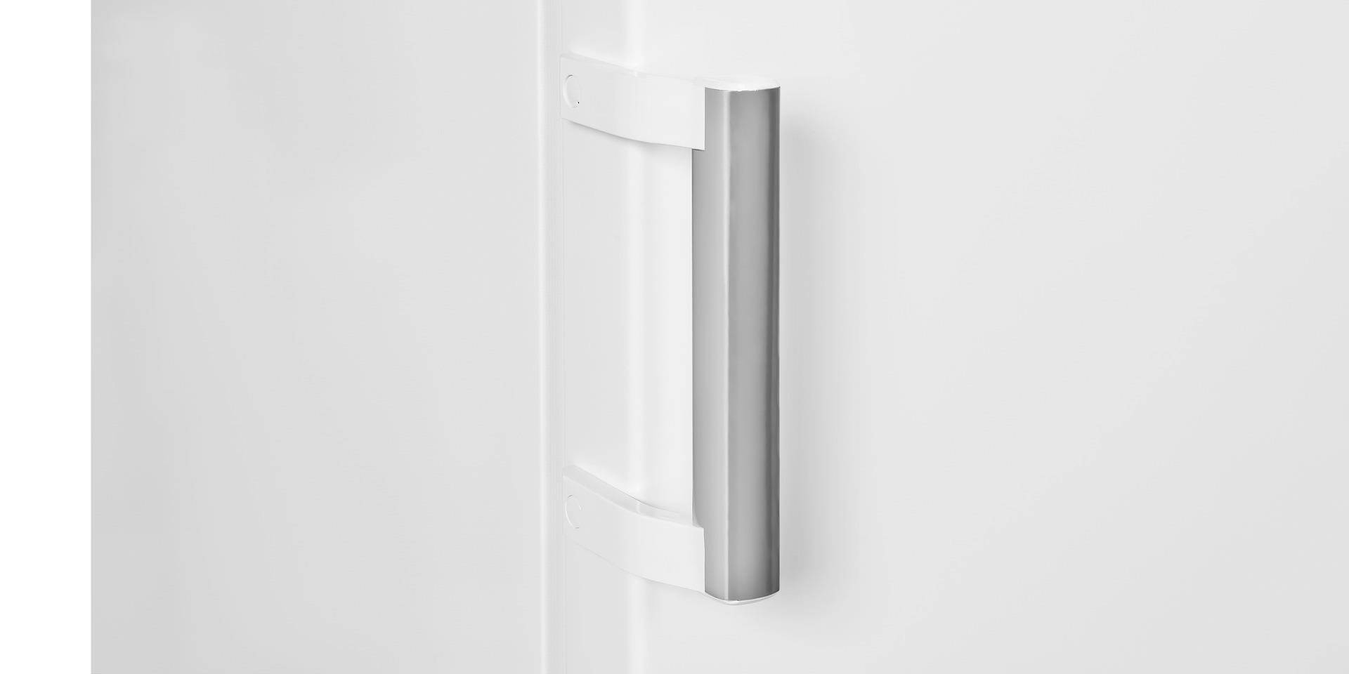 Ein weißer Kühlschrankgriff aus Metall an einer geschlossenen Tür, seitlich fotografiert.