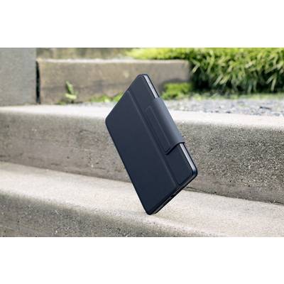 Ein geschlossenes Tablet in einer schwarzen Hülle schwebt über einer Steintreppe im Freien. Im Hintergrund sind grüne Pflanzen sichtbar.