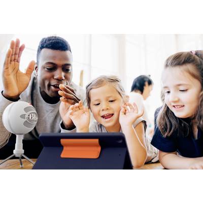 Ein Mann und zwei Kinder interagieren fröhlich mit einem Tablet und einem Mikrofon. Sie scheinen an einem digitalen Lernspiel teilzunehmen.