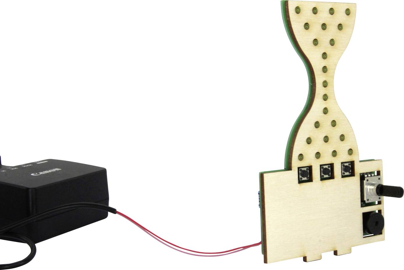 Eine sanduhrförmige Holzplatine mit LED-Glühbirnen ist mit einer Stromquelle verbunden. Die Anordnung erinnert an eine elektronische Schaltung.