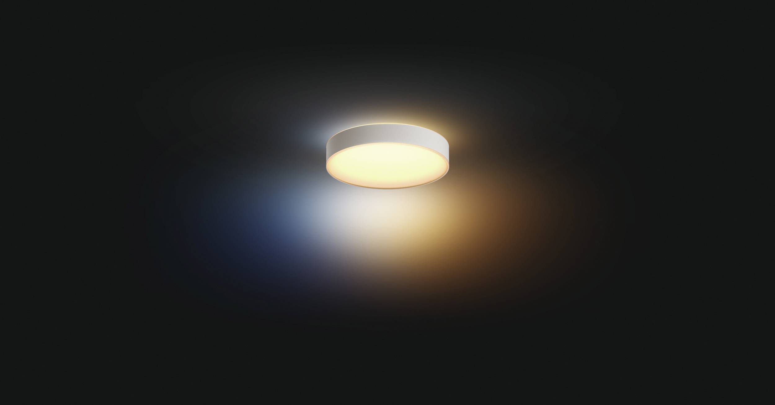 Eine runde Deckenleuchte strahlt warmes Licht aus, das sich auf einer glatten, dunklen Oberfläche in blauen und orangen Tönen widerspiegelt.