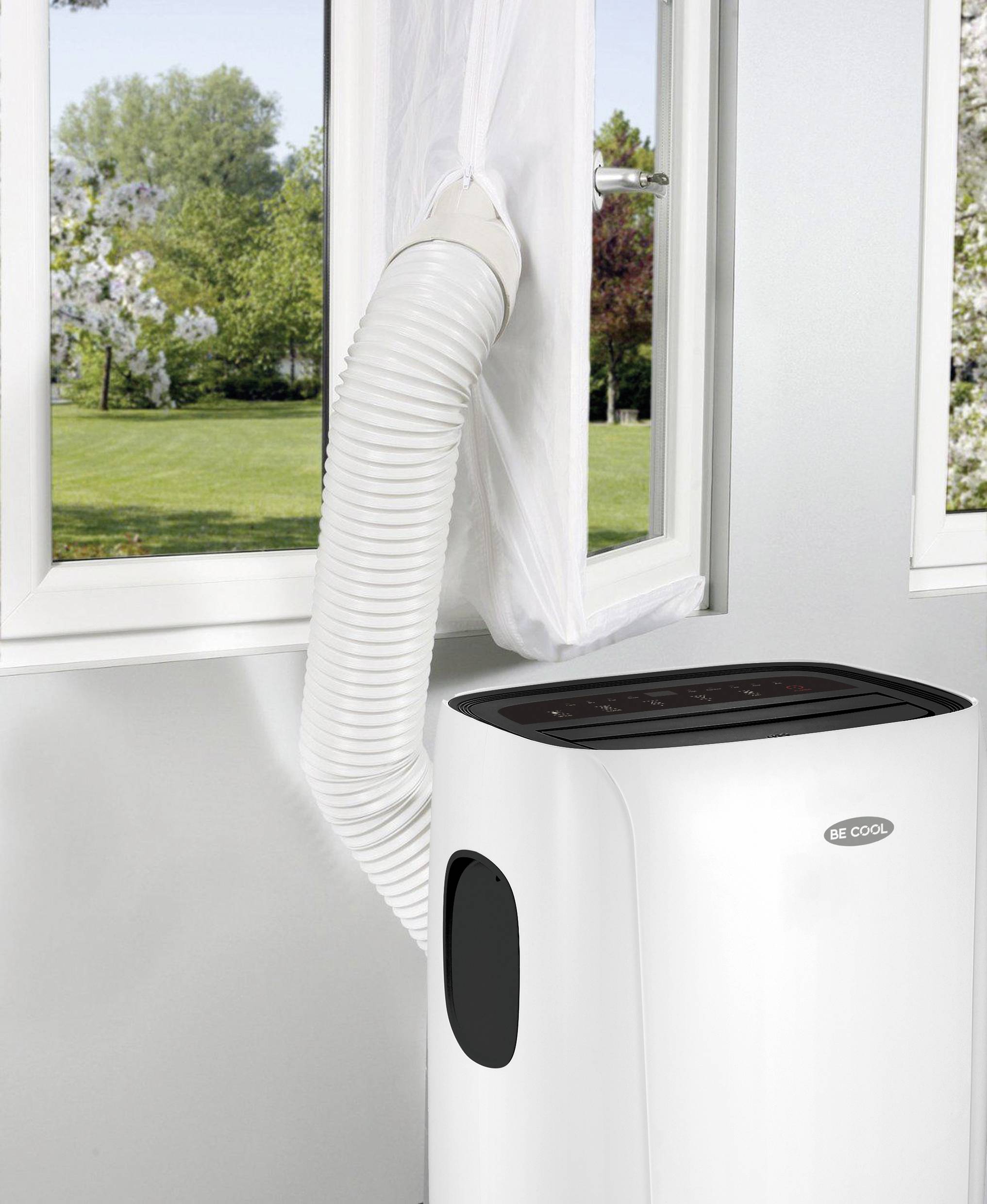 Mobiles Klimagerät mit Abluftschlauch, der durch ein geöffnetes Fenster ins Freie führt. Hintergrund zeigt einen sonnigen Garten.