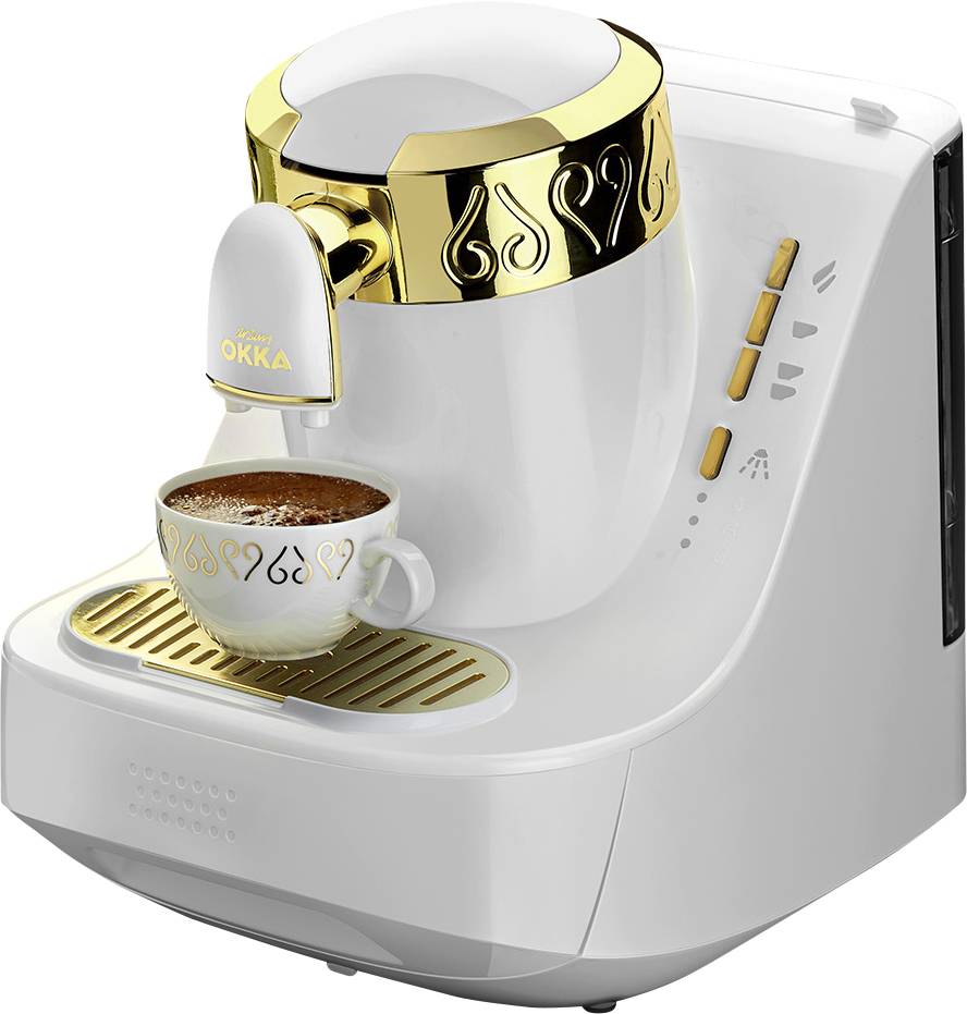 Weiße Kaffeemaschine mit goldenen Akzenten brüht Kaffee in eine weiße Tasse mit goldenen Mustern.