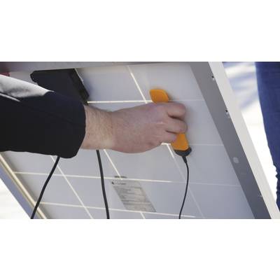 Eine Person hält ein Solarpanel und verwendet ein orangefarbenes Werkzeug. Kabel sind angeschlossen, was auf eine technische Überprüfung hindeutet.