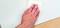 Eine Hand reinigt eine Fläche mit einem weißen Tuch auf einem Holzuntergrund.