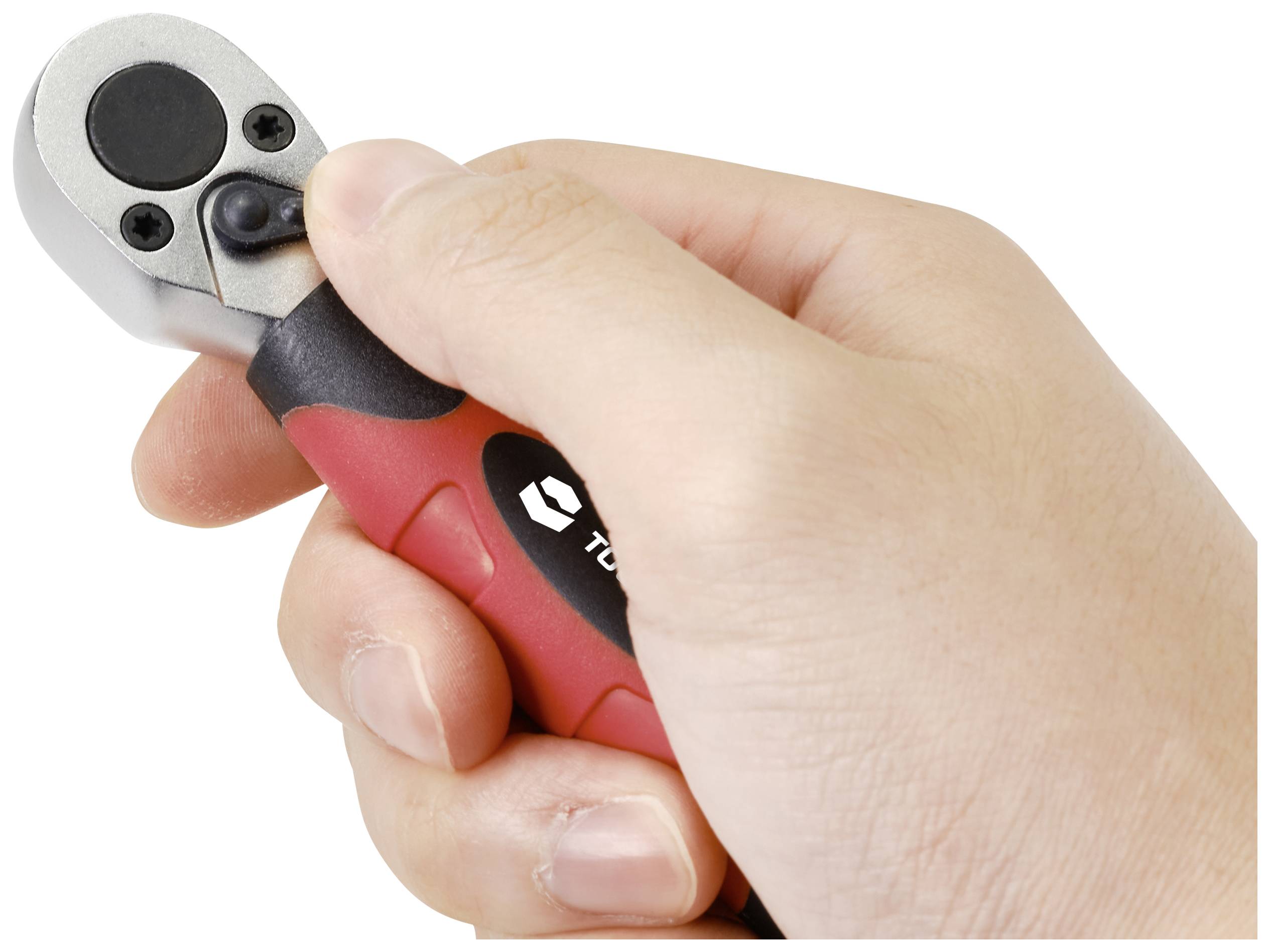 Eine Hand hält einen kleinen Ratschen-Schraubenschlüssel mit einem roten und schwarzen Griff.