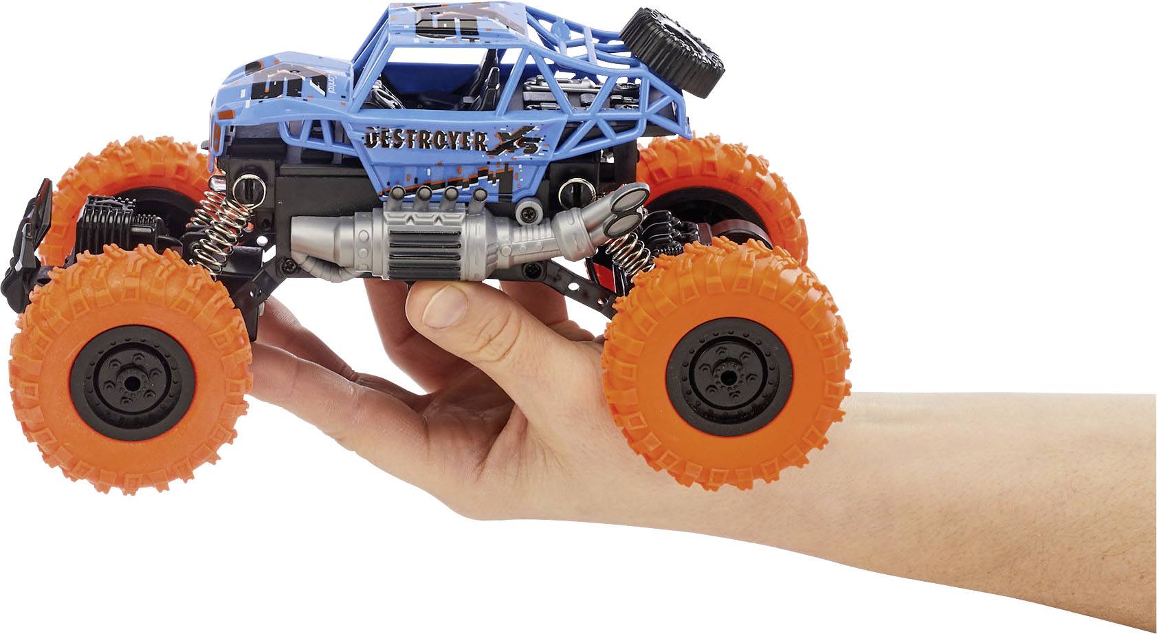 Spielzeug-Monstertruck mit blauen Rahmen und großen orangefarbenen Rädern wird in einer Hand gehalten.