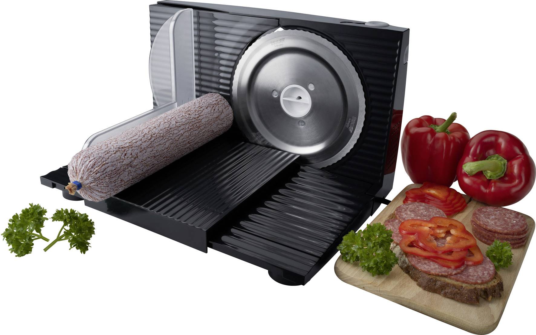 Elektrische Aufschnittmaschine schneidet eine länge Wurst. Daneben Paprika, Petersilie, und belegtes Brot auf einem Holzbrett.