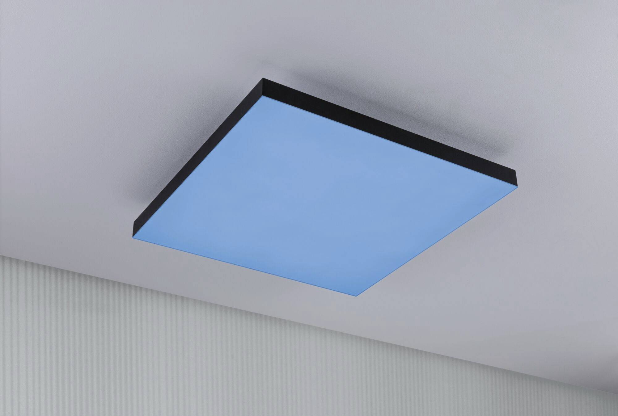 Blaue quadratische Deckenleuchte vor einem grauen Hintergrund.