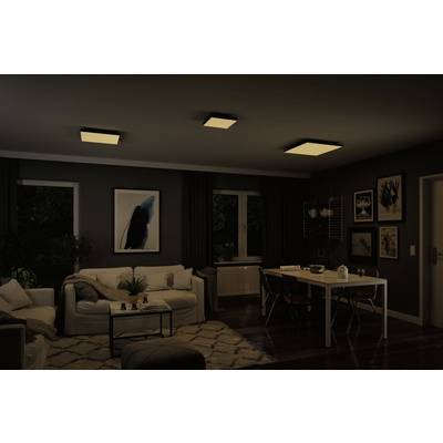 Ein modern eingerichtetes Wohnzimmer mit dunkler Wandfarbe. Die Beleuchtung besteht aus drei Deckenleuchten. Ein Bild hängt über dem Sofa.