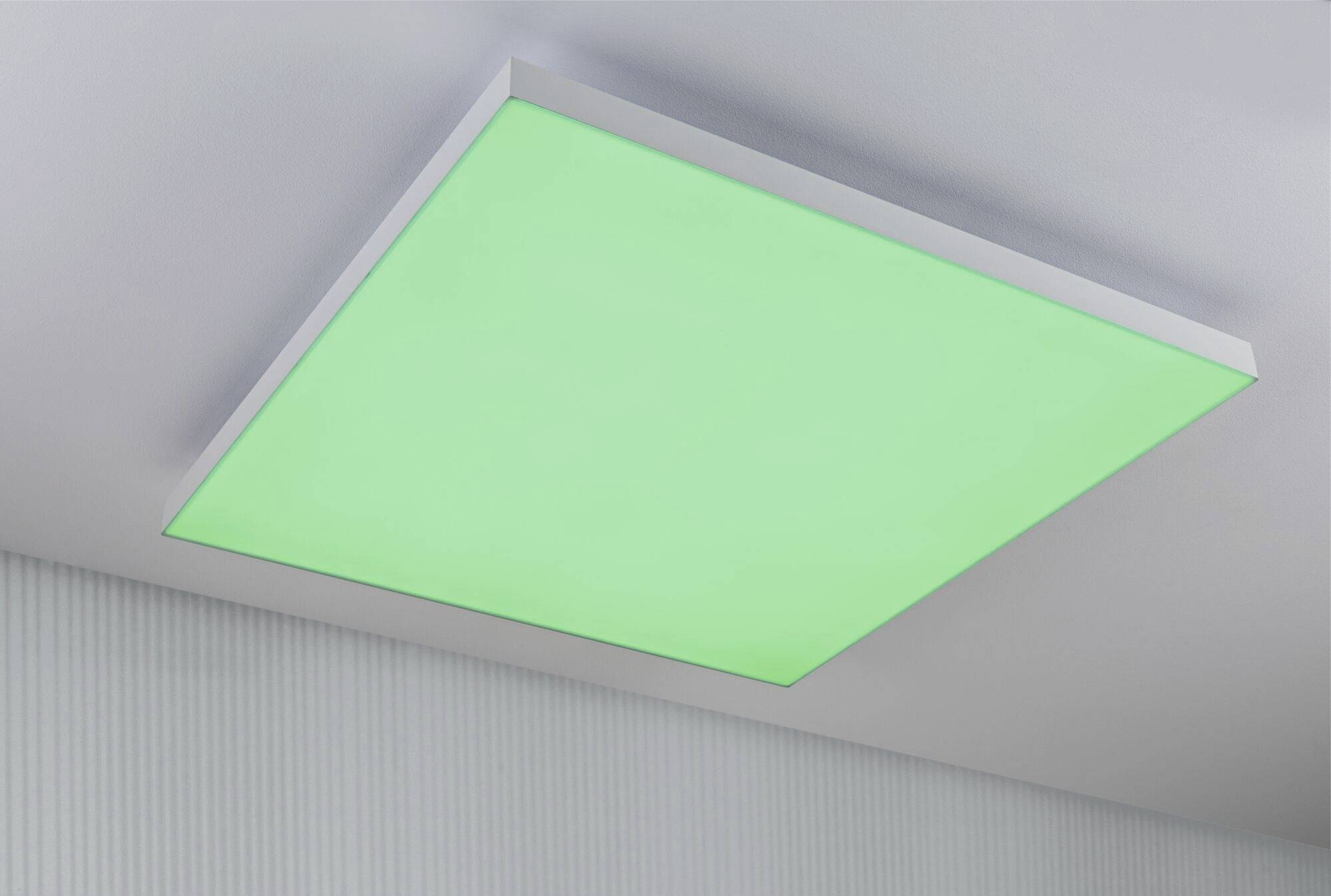 Quadratische, grün leuchtende Deckenlampe in einem modernen Raum.