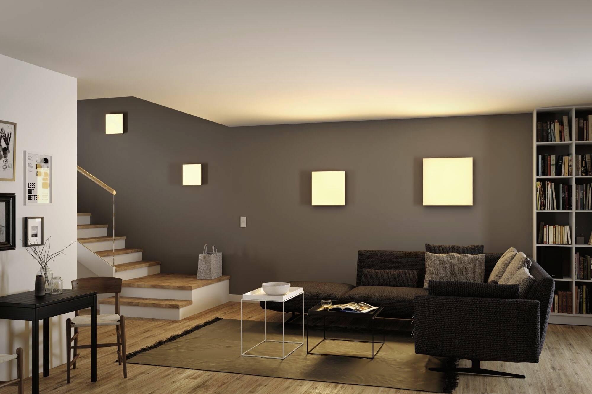 Ein modernes Wohnzimmer mit dunklem Sofa, Couchtisch und Wandkunst. Im Hintergrund eine Treppe und Bücherregal.