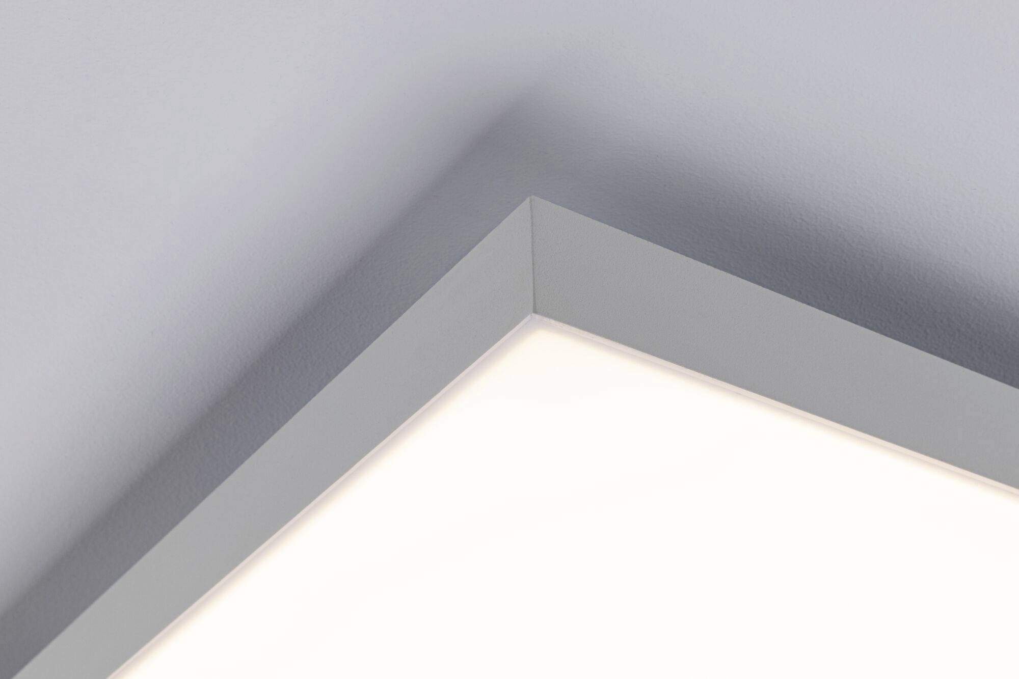 Ecke eines hell erleuchteten Deckenpaneels in einem modernen Raum, das minimalistisches Design und gleichmäßige Beleuchtung zeigt.