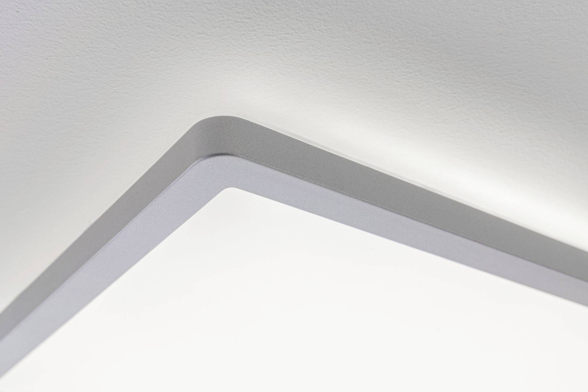 Ecke einer modernen, rechteckigen LED-Deckenleuchte mit glattem, minimalistischem Design in einem hellen Raum.
