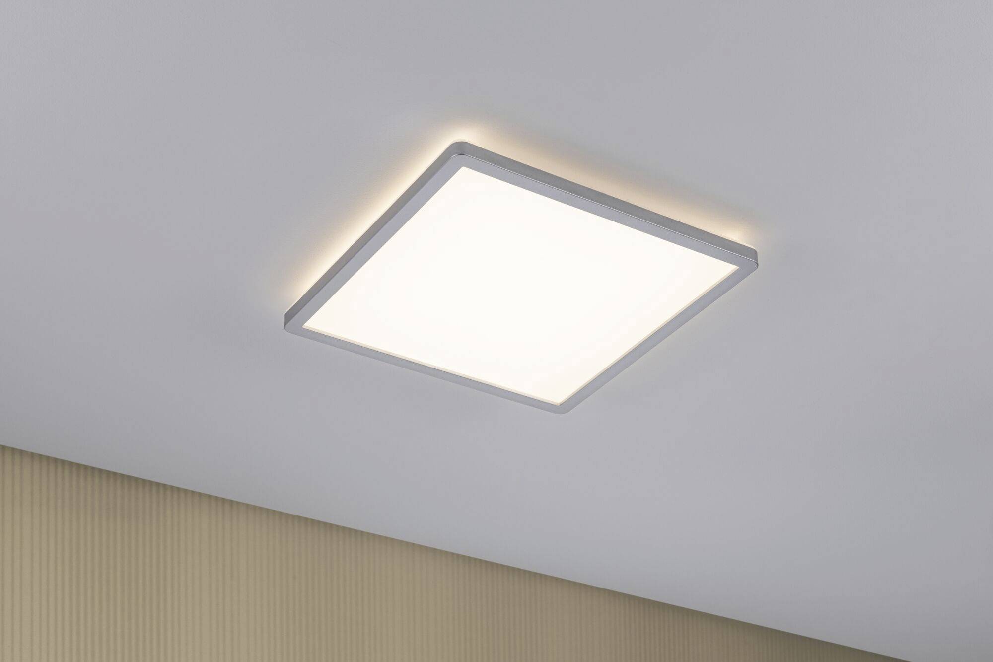 Eine quadratische Deckenlampe mit sanft leuchtendem weißem Licht, montiert an einer weißen Decke, beleuchtet einen Raum.